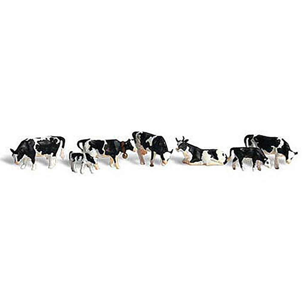 A set of small black-and-white cow figurines, including several adults and a few calves, arranged in a line on a plain white background.