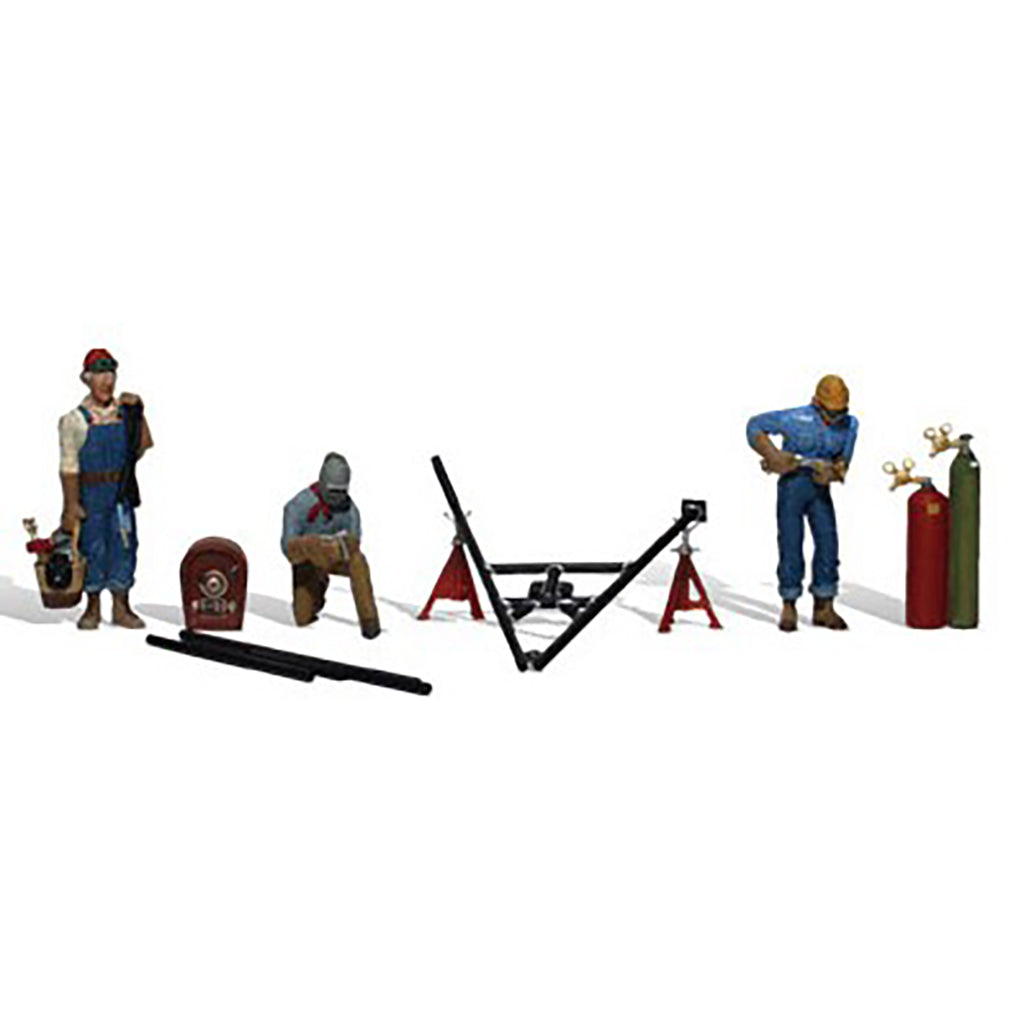 A miniature model set of four construction workers with various tools and equipment, including a welding helmet, a red toolbox, a black metal frame, red support stands, and gas cylinders, displayed on a clean white background.