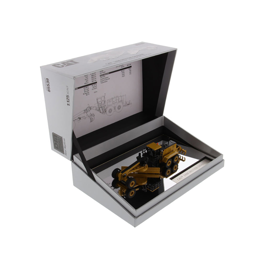 A boxed miniature construction vehicle set displayed open on a white background. The set includes a small yellow and black road grader model inside a gray presentation box with printed instructions or technical drawings visible inside the lid.