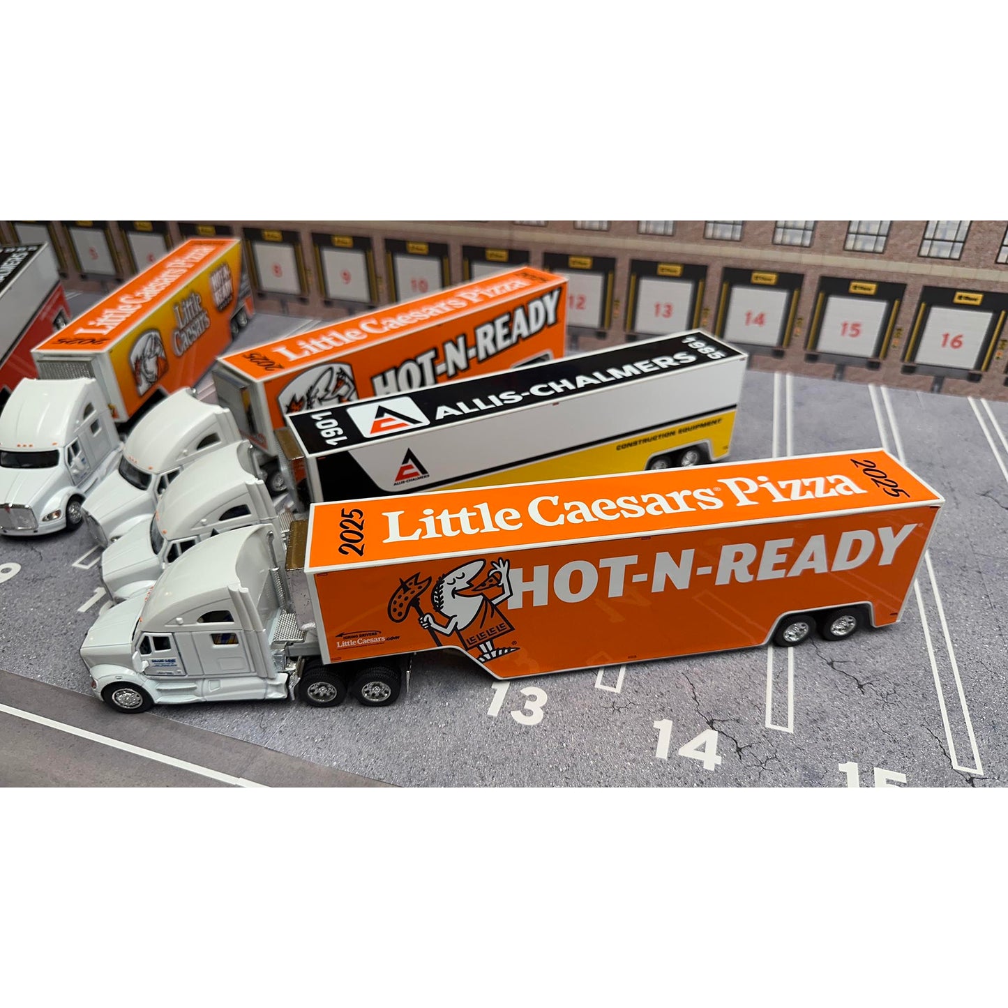 Model trucks with Little Caesars Pizza and Allis Chalmers branding on a parking lot background.