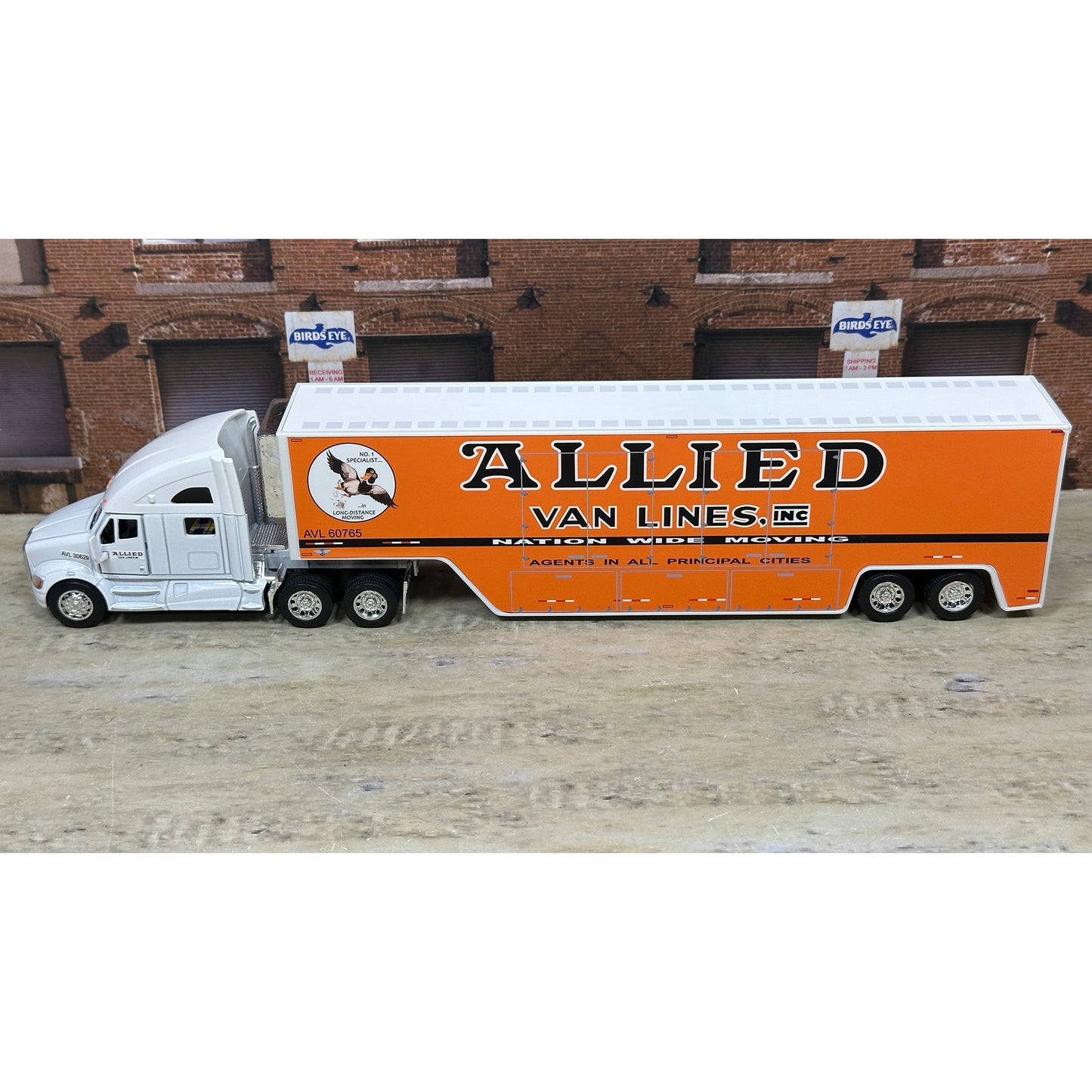 Model truck with 'Allied Van Lines' branding on a wooden surface.