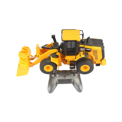 Radio controlled model of a CAT yellow & black Caterpillar 950M wheel loader with controller on a white background