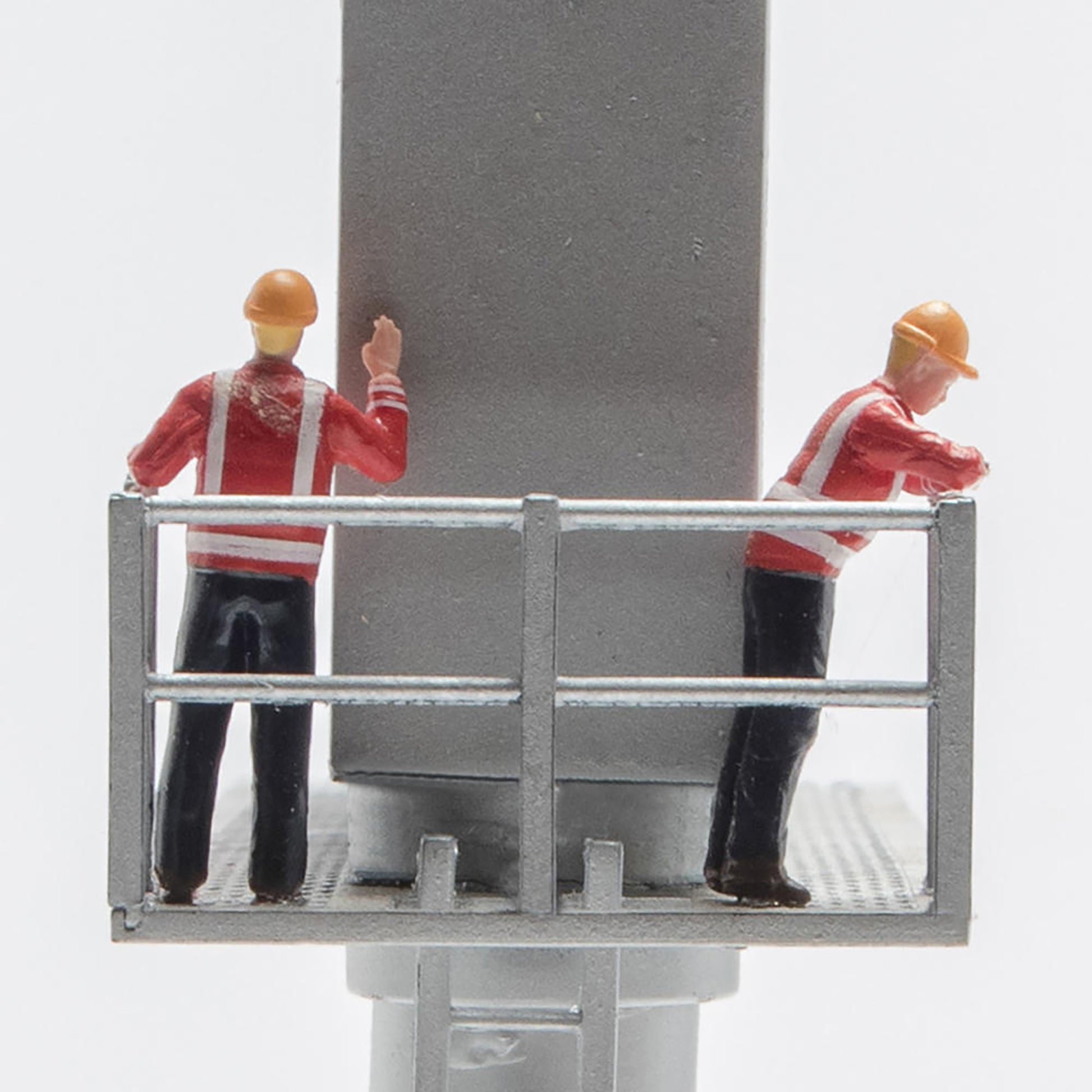 Model figures of workers on a platform with a large cylindrical object.