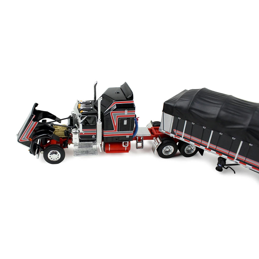 A die-cast model of a classic Kenworth semi-truck with a black and red cab, towing a long black canvas-covered trailer, shown on a plain white background.