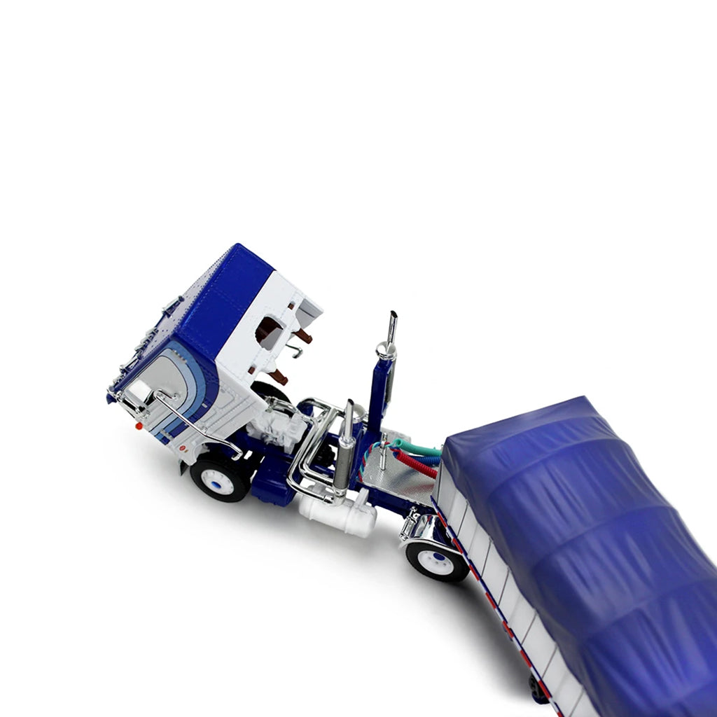 A die-cast model of a classic Peterbilt Cab-Over semi-truck with a White and blue cab, towing a long white with blue canvas-covered trailer, shown on a plain white background.