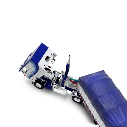 A die-cast model of a classic Peterbilt Cab-Over semi-truck with a White and blue cab, towing a long white with blue canvas-covered trailer, shown on a plain white background.