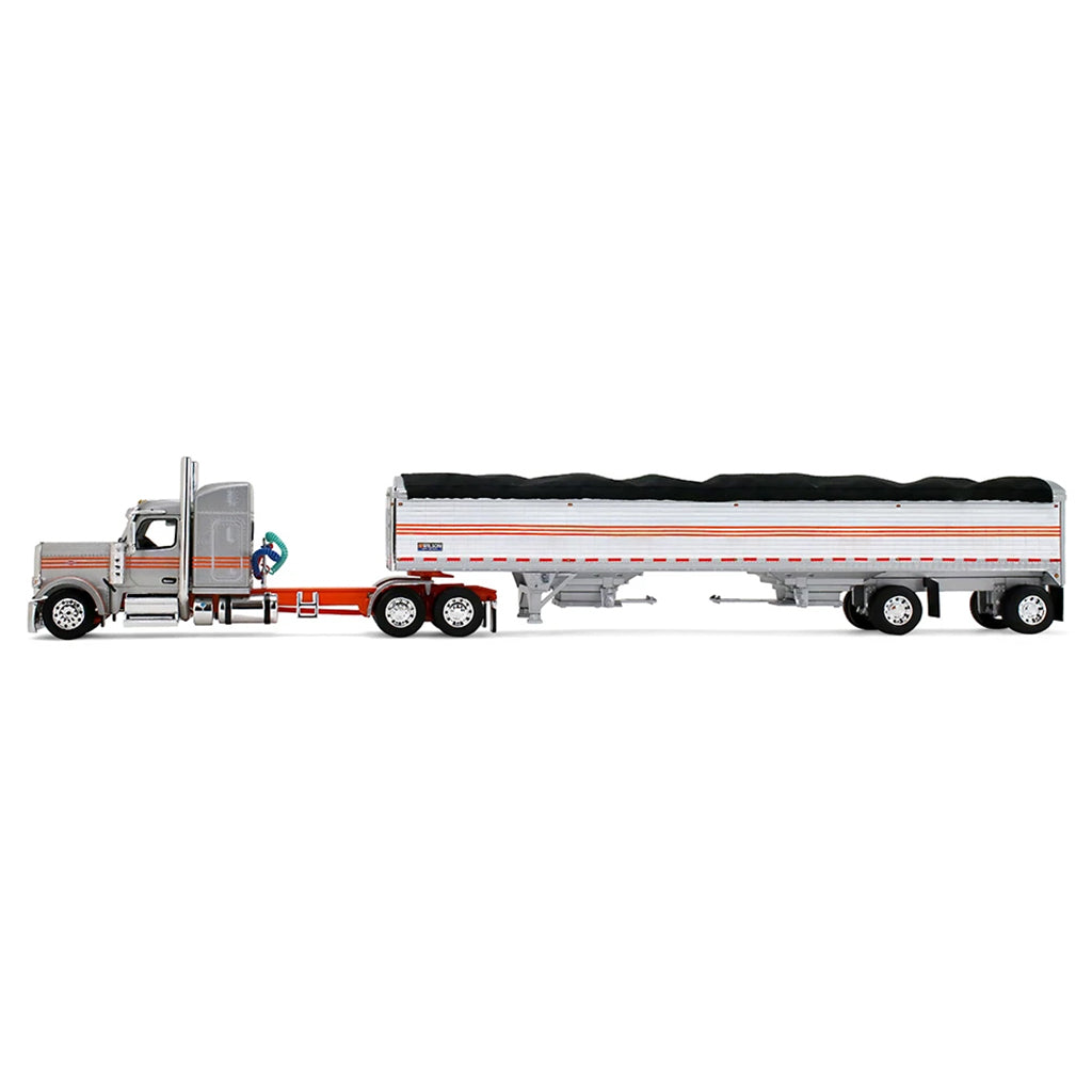 A diecast model of a Peterbilt semi-truck pulling a white grain trailer with orange stripes and a black tarp, on a white background.
