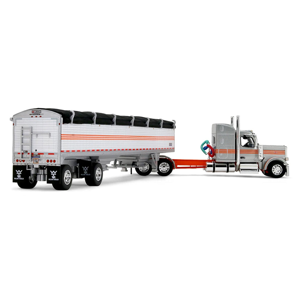 A diecast model of a Peterbilt semi-truck pulling a white grain trailer with orange stripes and a black tarp, on a white background.