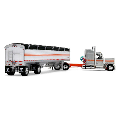A diecast model of a Peterbilt semi-truck pulling a white grain trailer with orange stripes and a black tarp, on a white background.