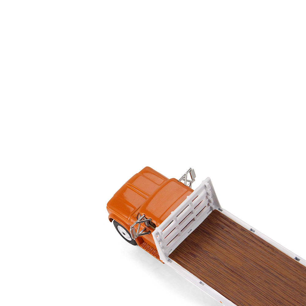An orange GMC flatbed truck model with a white flatbed and white wheels, shown on a clean white background.