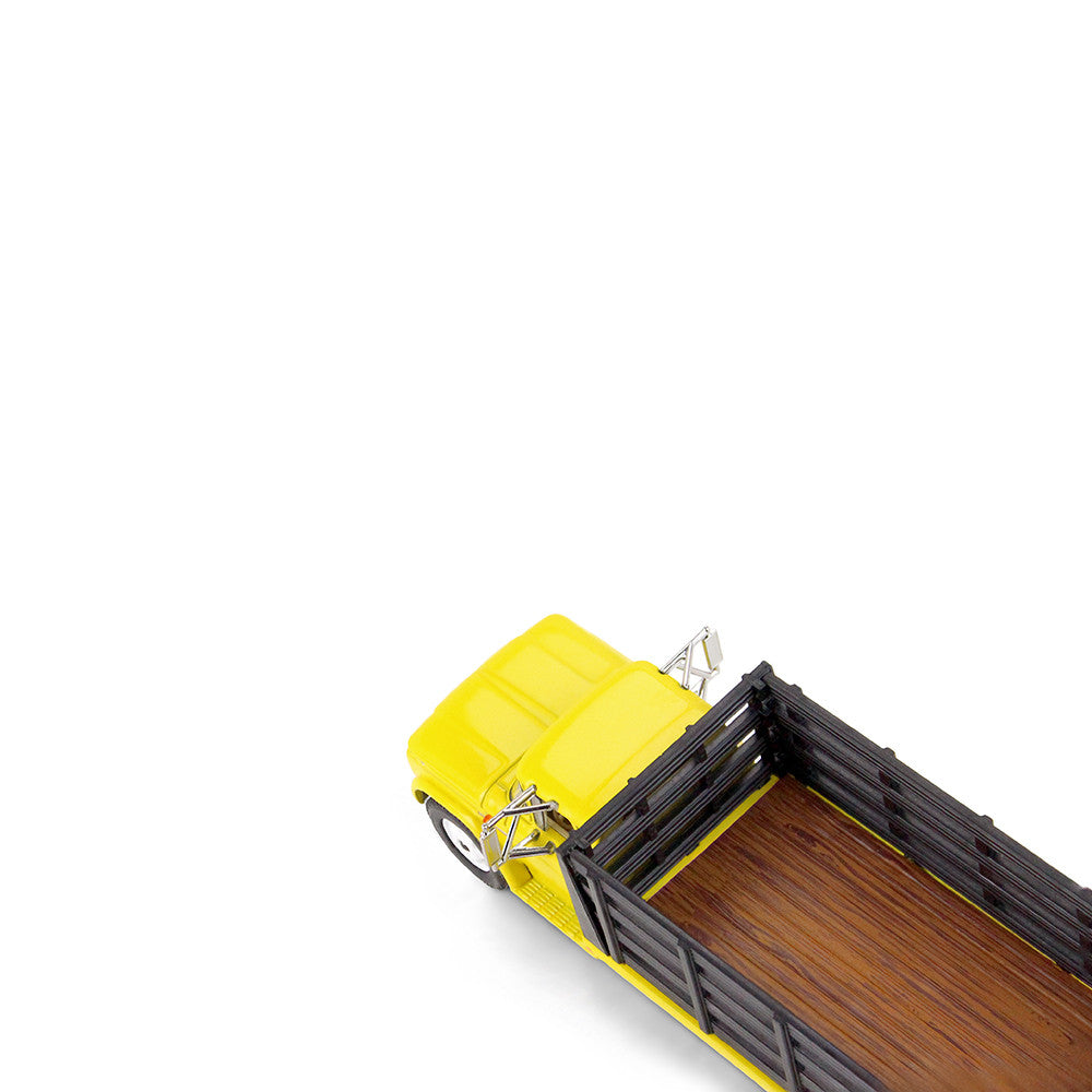 A yellow vintage GMC stake truck with a black slatted cargo bed on a clean white background.