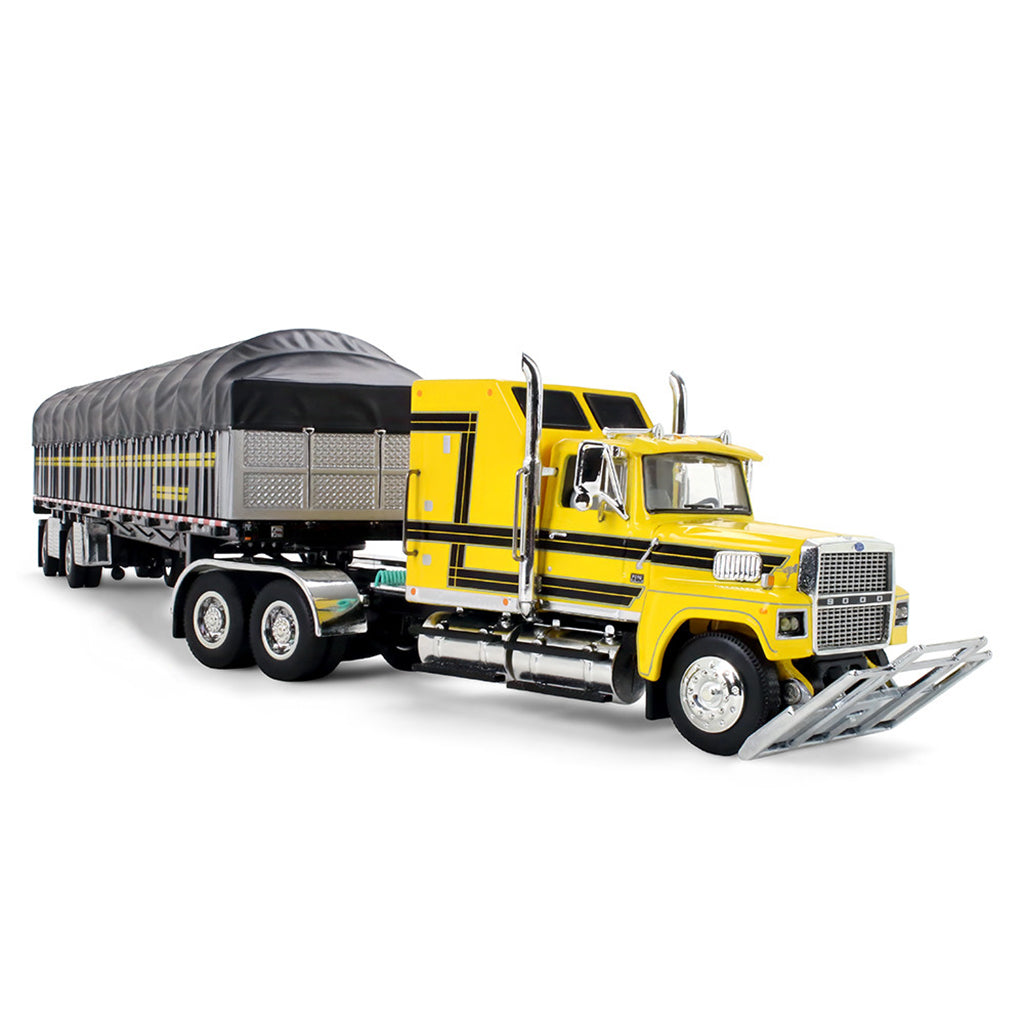 A model of a yellow semi-truck pulling a long black covered wagon trailer with yellow stripes, shown on a plain white background.