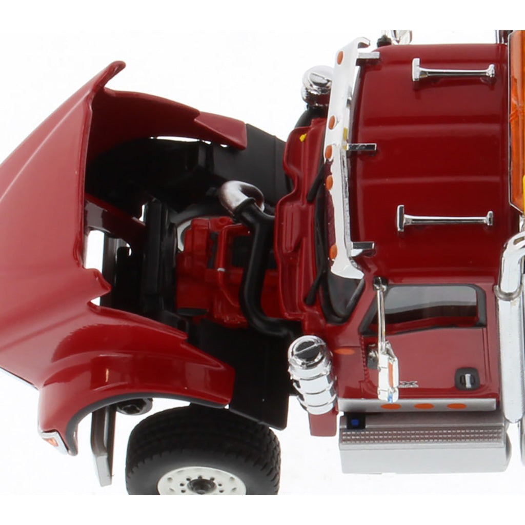 A close-up of a red toy semi-truck cab with an open hood showing a red engine compartment, black wheels, chrome details, and orange reflective accents on a white background.