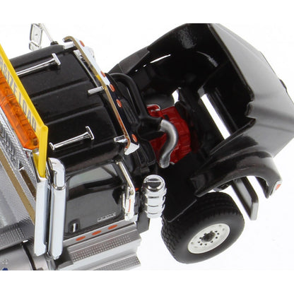 A close-up of a black toy semi-truck cab with an open hood showing a red engine compartment, black wheels, chrome details, and orange reflective accents on a white background.