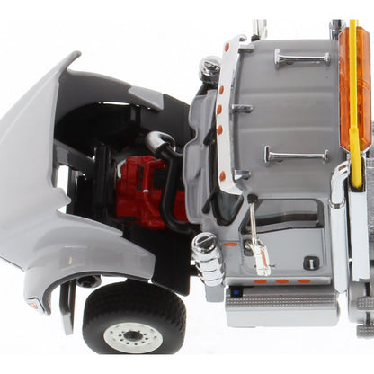 A close-up of a gray toy semi-truck cab with an open hood showing a red engine compartment, black wheels, chrome details, and orange reflective accents on a white background.