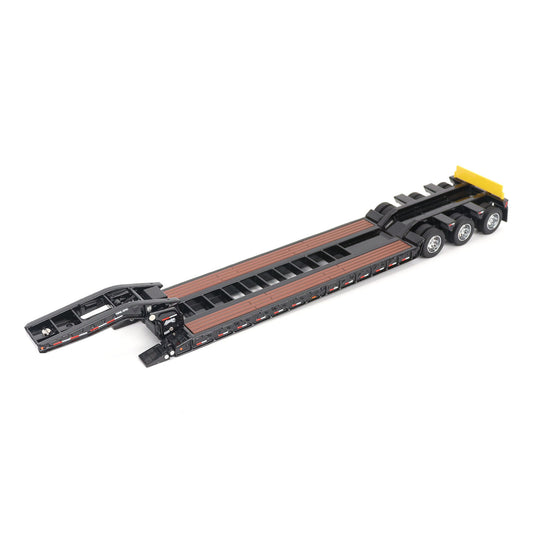 A miniature toy model of a Trail King TK120 lowboy trailer with a black frame, brown textured deck, and a yellow sign, shown on a solid white background.