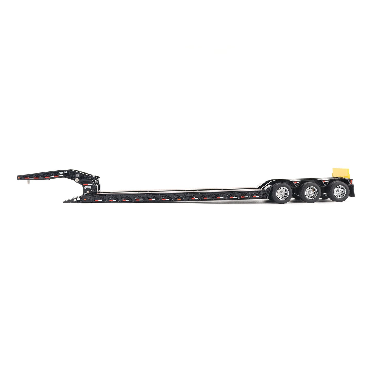 A miniature toy model of a Trail King TK120 lowboy trailer with a black frame, brown textured deck, and a yellow sign, shown on a solid white background.