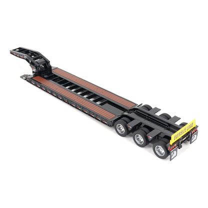 A miniature toy model of a Trail King TK120 lowboy trailer with a black frame, brown textured deck, and a yellow sign, shown on a solid white background.