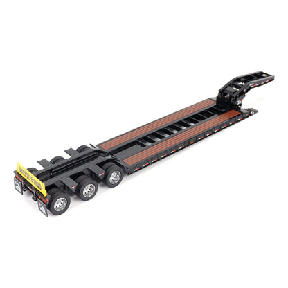 A miniature toy model of a Trail King TK120 lowboy trailer with a black frame, brown textured deck, and a yellow sign, shown on a solid white background.