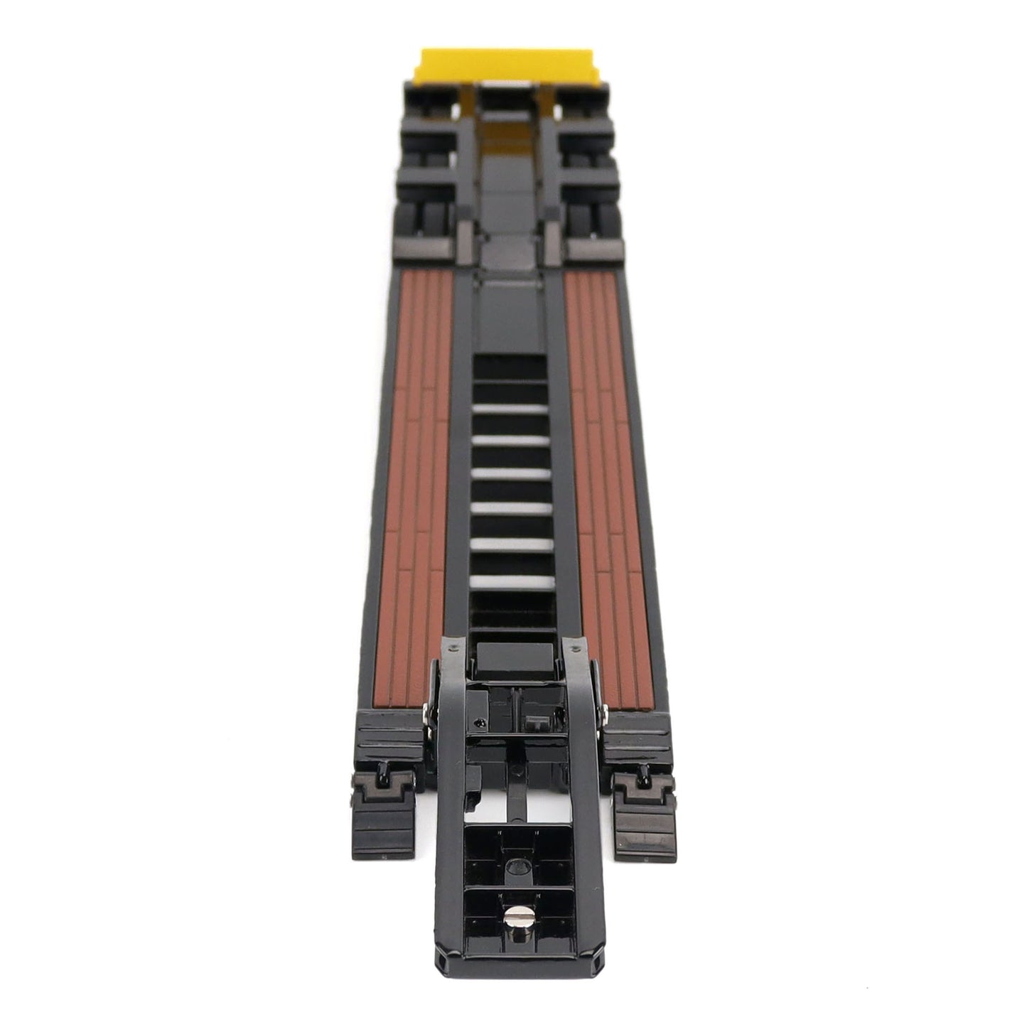 A miniature toy model of a Trail King TK120 lowboy trailer with a black frame, brown textured deck, and a yellow sign, shown on a solid white background.
