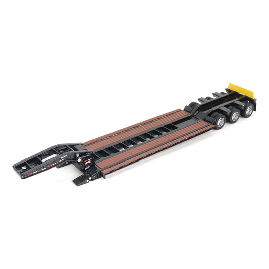 A miniature toy model of a Trail King TK120 lowboy trailer with a black frame, brown textured deck, and a yellow sign, shown on a solid white background.
