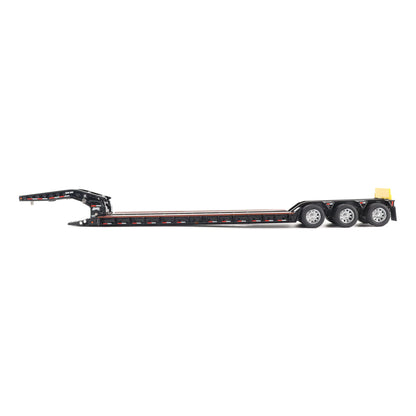 A miniature toy model of a Trail King TK120 lowboy trailer with a black frame, brown textured deck, and a yellow sign, shown on a solid white background.