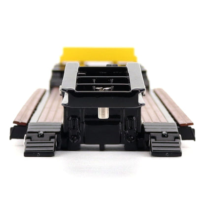 A miniature toy model of a Trail King TK120 lowboy trailer with a black frame, brown textured deck, and a yellow sign, shown on a solid white background.