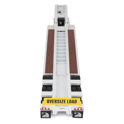 A miniature toy model of a Trail King TK120 lowboy trailer with a black frame, brown textured deck, and a yellow sign, shown on a solid white background.