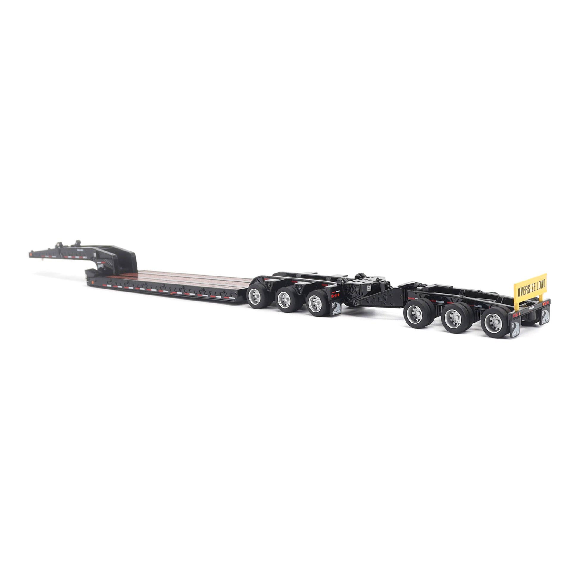 A miniature toy model of a Trail King TK120 lowboy trailer with a black frame, brown textured deck, and a yellow sign, shown on a solid white background.