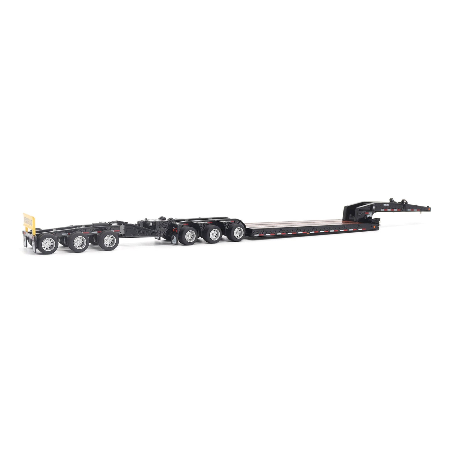 A miniature toy model of a Trail King TK120 lowboy trailer with a black frame, brown textured deck, and a yellow sign, shown on a solid white background.