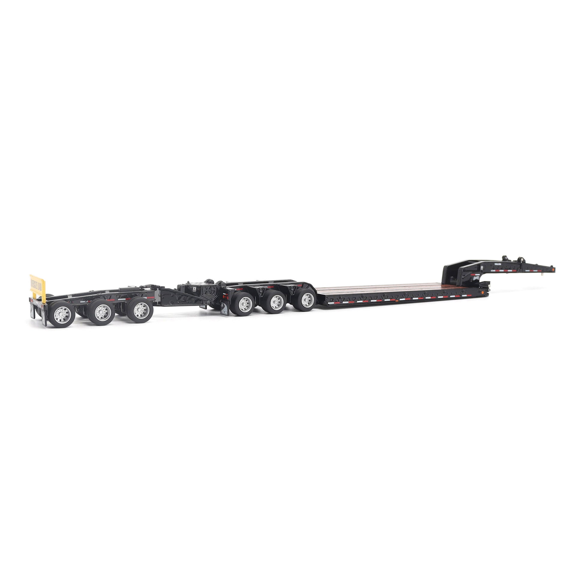 A miniature toy model of a Trail King TK120 lowboy trailer with a black frame, brown textured deck, and a yellow sign, shown on a solid white background.