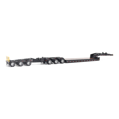 A miniature toy model of a Trail King TK120 lowboy trailer with a black frame, brown textured deck, and a yellow sign, shown on a solid white background.