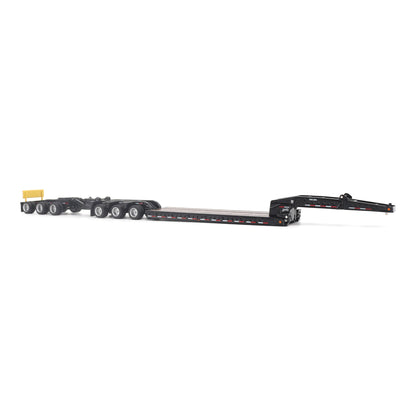 A miniature toy model of a Trail King TK120 lowboy trailer with a black frame, brown textured deck, and a yellow sign, shown on a solid white background.