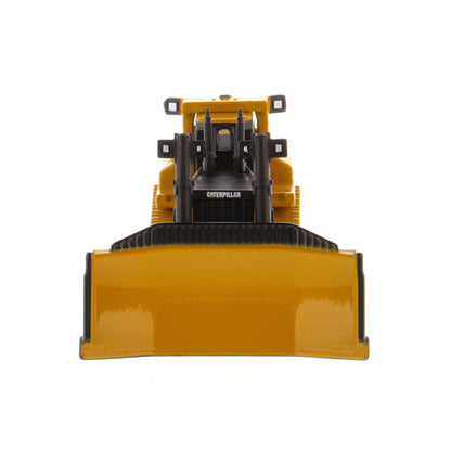 A yellow and black toy bulldozer with a large front blade, shown from the front against a plain white background. The brand name 'CATERPILLAR' is visible on the side of the engine housing.