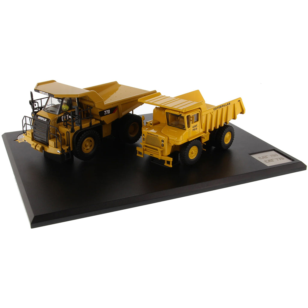 Models of Caterpillar 769 Off Highway Dump Truck (1963-1965) & Caterpillar 770 Off Highway Dump Truck (2013-Current) Mounted on a Black Base on a White Background