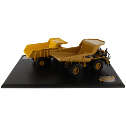 Models of Caterpillar 769 Off Highway Dump Truck (1963-1965) & Caterpillar 770 Off Highway Dump Truck (2013-Current) Mounted on a Black Base on a White Background