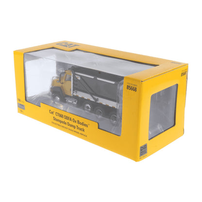 A yellow and black Cat CT660 5BFA Ox Bodies stampede dump truck model in its original packaging, shown on a plain white background.