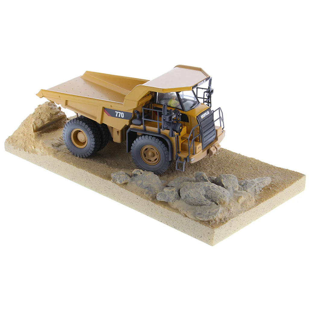 Model of a Weathered Caterpillar 770 Off-Highway Dump Truck Mounted on a Simulated Dirt & Rock Base on a White Background