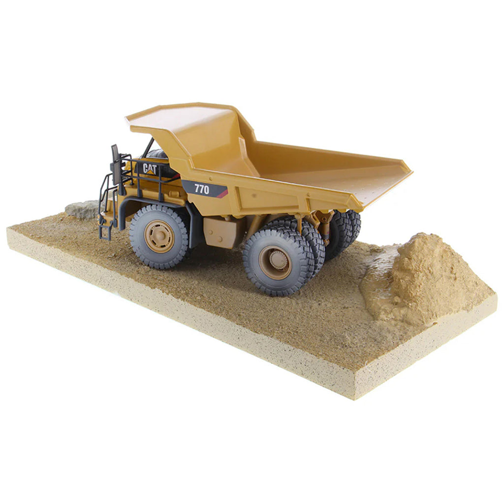 Model of a Weathered Caterpillar 770 Off-Highway Dump Truck Mounted on a Simulated Dirt & Rock Base on a White Background