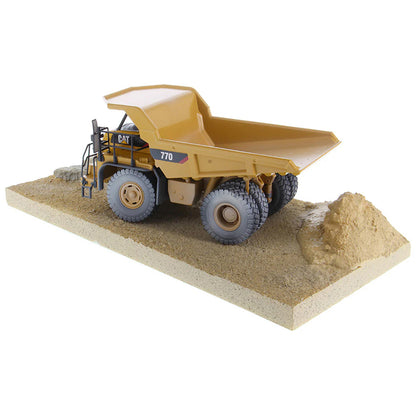 Model of a Weathered Caterpillar 770 Off-Highway Dump Truck Mounted on a Simulated Dirt & Rock Base on a White Background