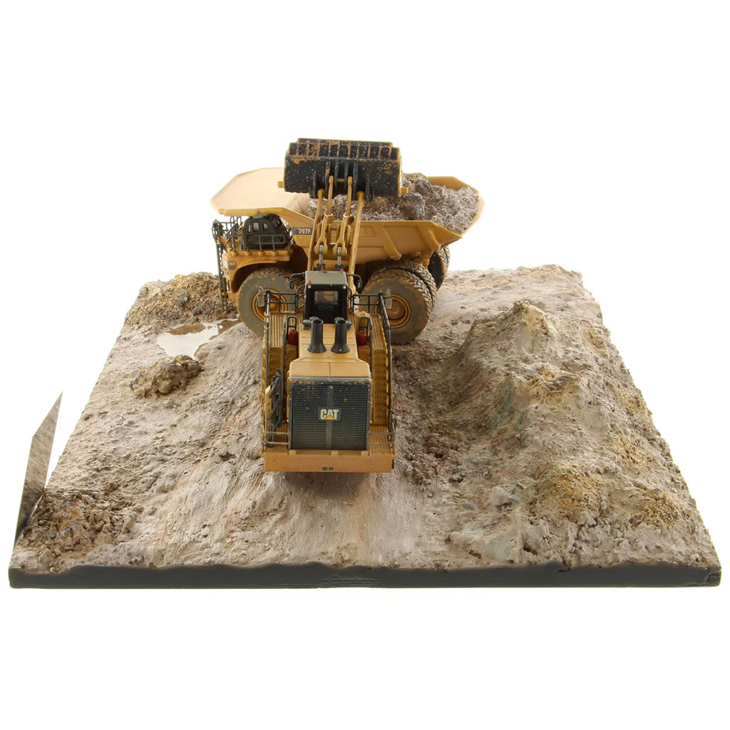 Model of a Caterpillar 994K Wheel Loader Loading a Model of a CAT 797 Mining Dump Truck Attached to a Base That is Made to Look Like a Rock & Dirt Construction Site on a White Background