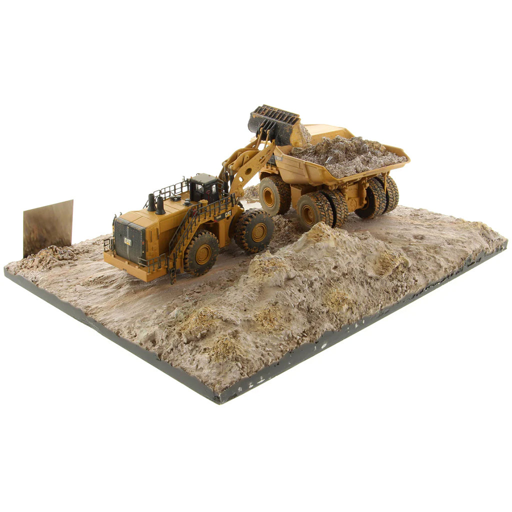 Model of a Caterpillar 994K Wheel Loader Loading a Model of a CAT 797 Mining Dump Truck Attached to a Base That is Made to Look Like a Rock & Dirt Construction Site on a White Background