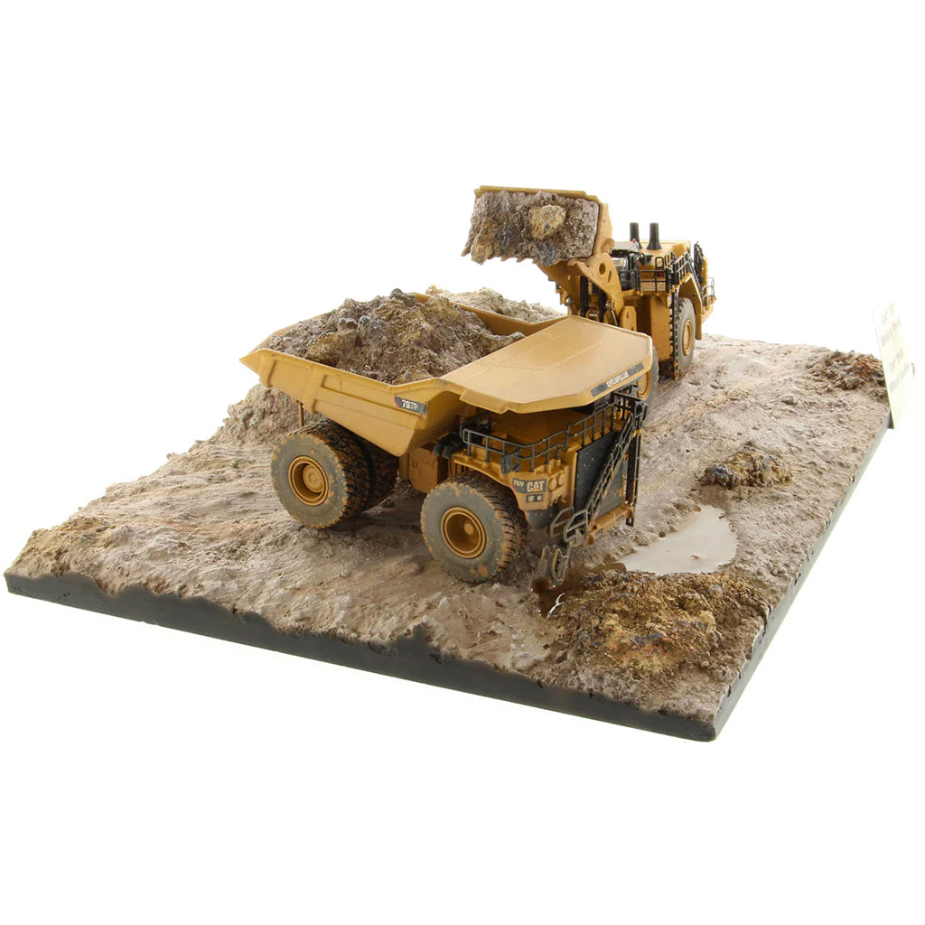 Model of a Caterpillar 994K Wheel Loader Loading a Model of a CAT 797 Mining Dump Truck Attached to a Base That is Made to Look Like a Rock & Dirt Construction Site on a White Background