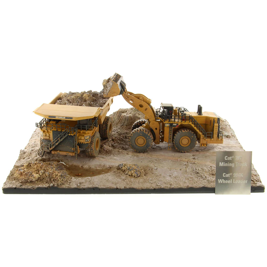 Model of a Caterpillar 994K Wheel Loader Loading a Model of a CAT 797 Mining Dump Truck Attached to a Base That is Made to Look Like a Rock & Dirt Construction Site on a White Background