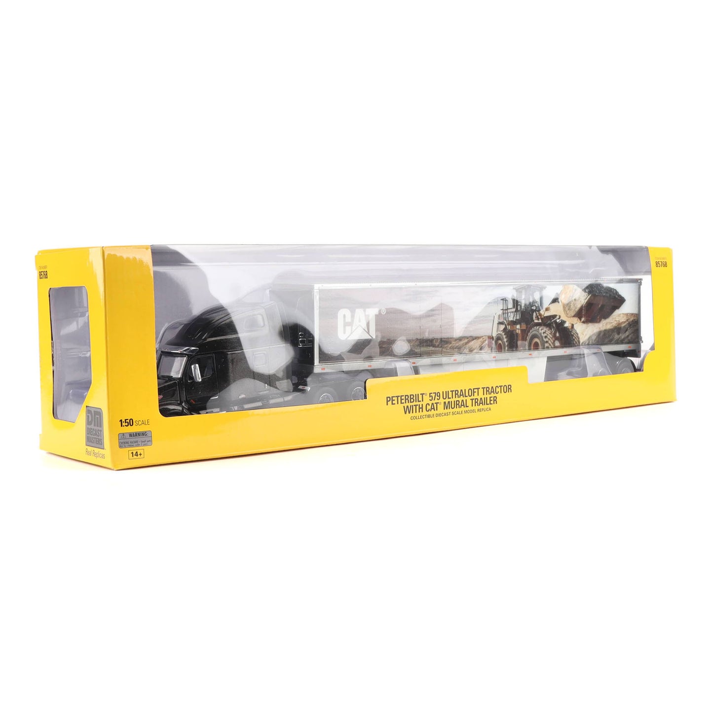 A yellow and clear plastic retail box containing a model toy of a Cat tractor trailer shown on a white background.