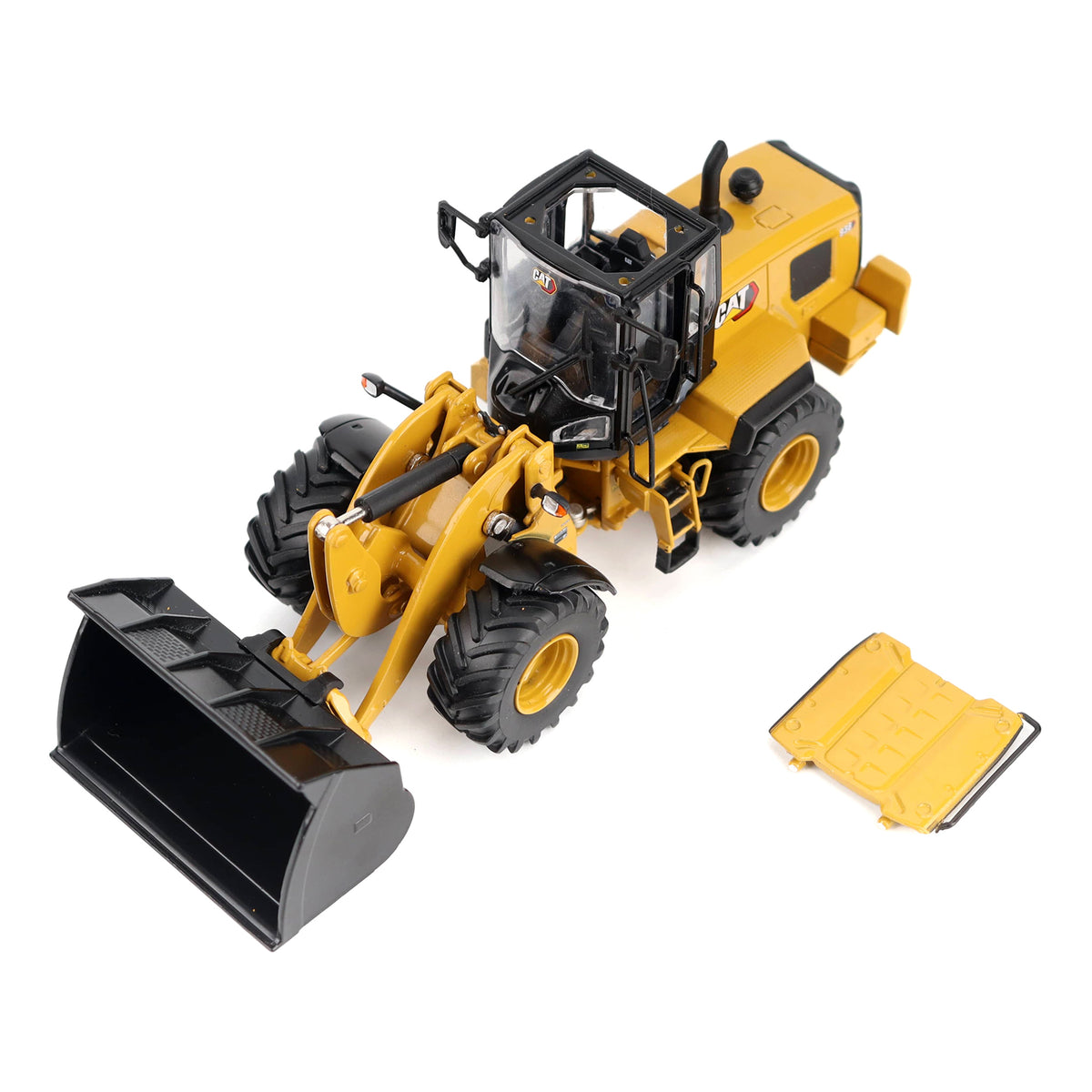 Yellow and black CAT wheel loader toy or model shown on a clean white background, with a separate yellow cover or panel placed beside it.
