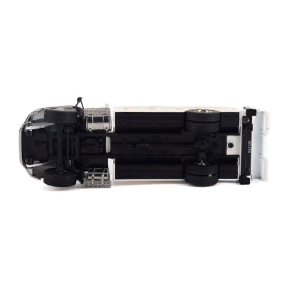 A miniature diecast model of a white and black service truck shown from underneath, revealing the detailed black chassis, wheels, and undercarriage, on a solid white background.