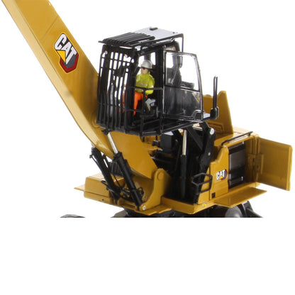 A yellow CAT excavator model with a black cab enclosure, hydraulic arms, and a small driver figure inside, photographed on a plain white background.