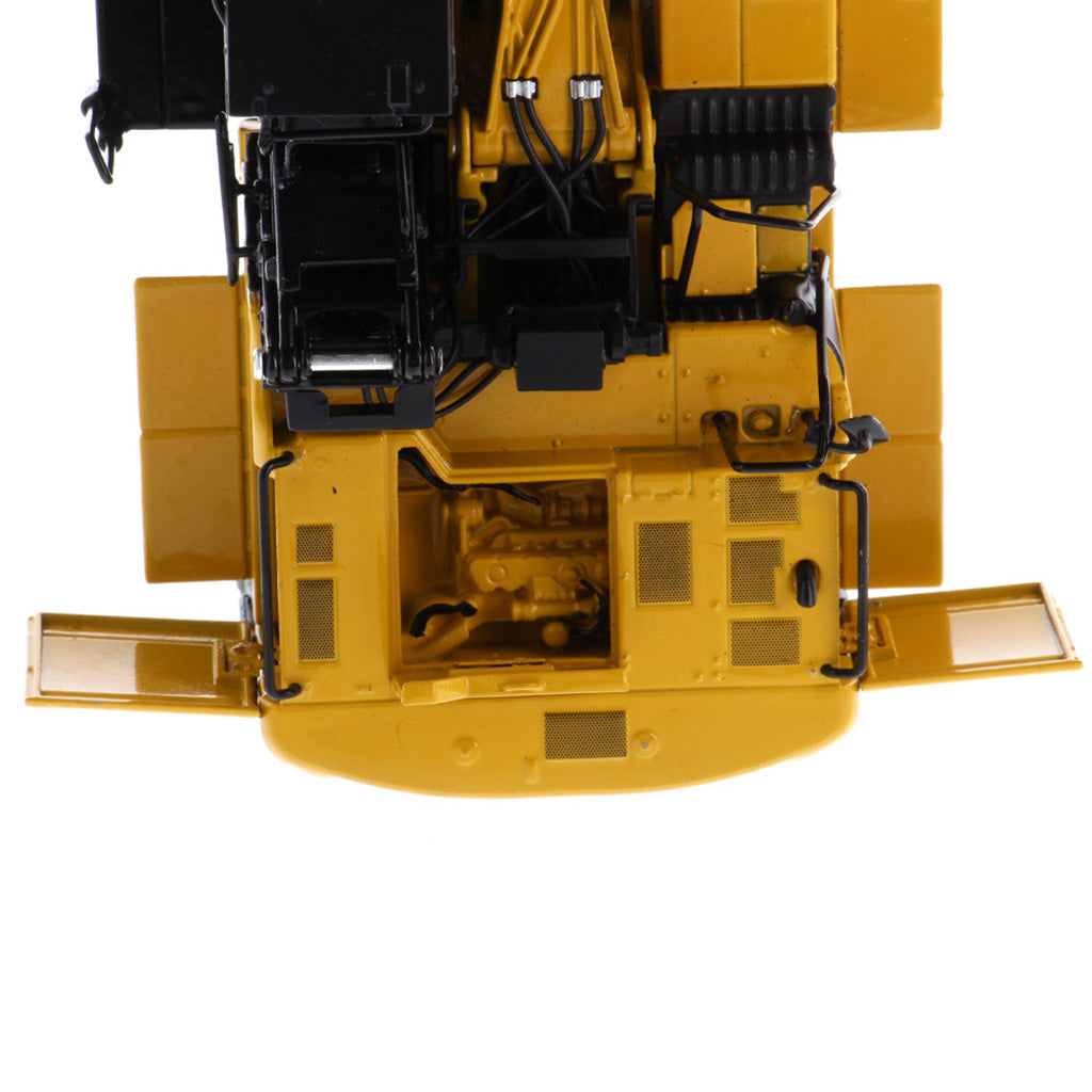 Close-up of the underside and rear compartment of a yellow construction vehicle, showing mechanical details, wiring, grilles, and side panels on a white background.