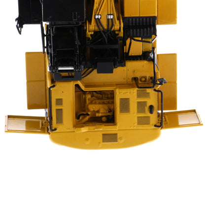 Close-up of the underside and rear compartment of a yellow construction vehicle, showing mechanical details, wiring, grilles, and side panels on a white background.
